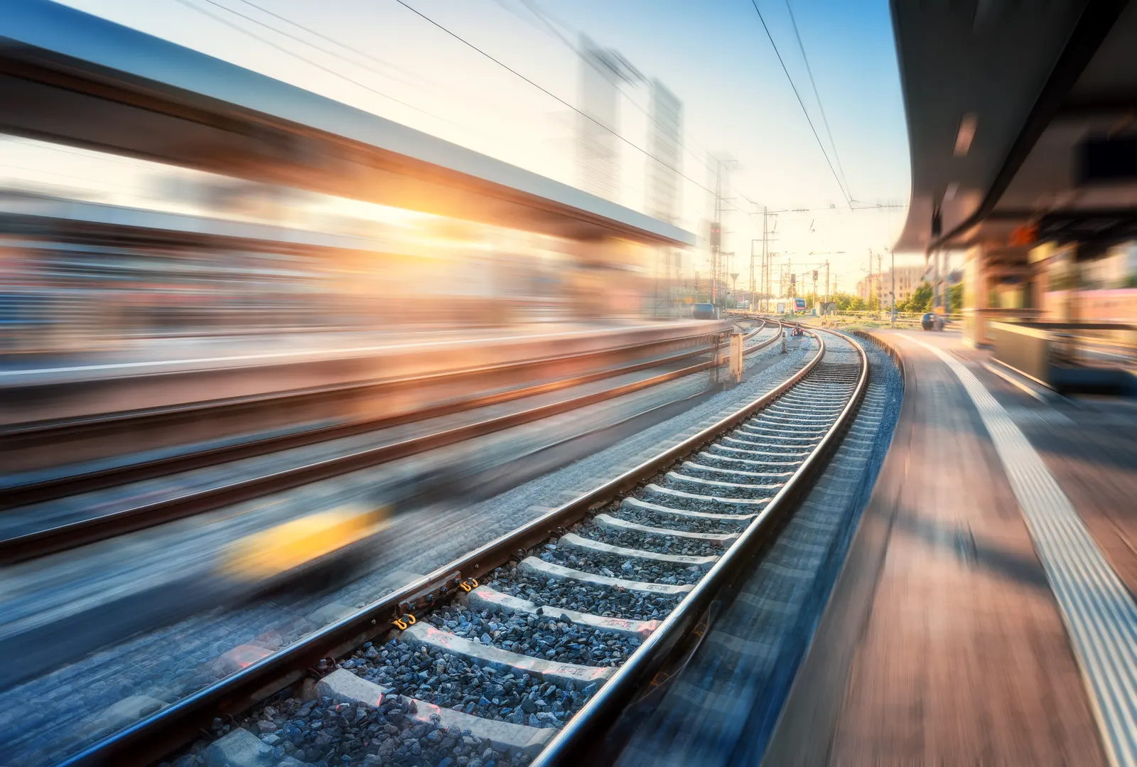 A train passing through a Swedish railway station at sunset, blurred with motion